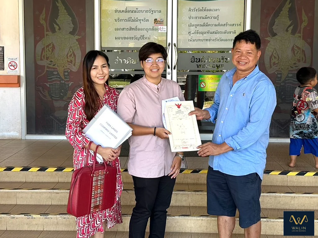 An archived photograph of Walin with clients holding a property document outside the land office.
